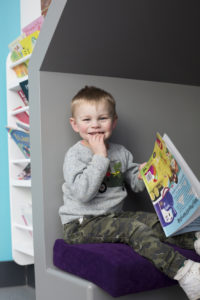Little boy sitting happily in the story corner
